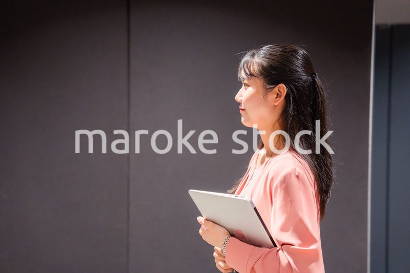 オフィスのロッカーの前でパソコンを持つ若い女性