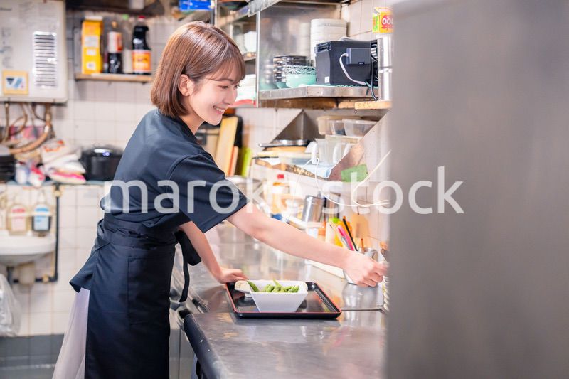 居酒屋の厨房で働くキッチンスタッフの女性