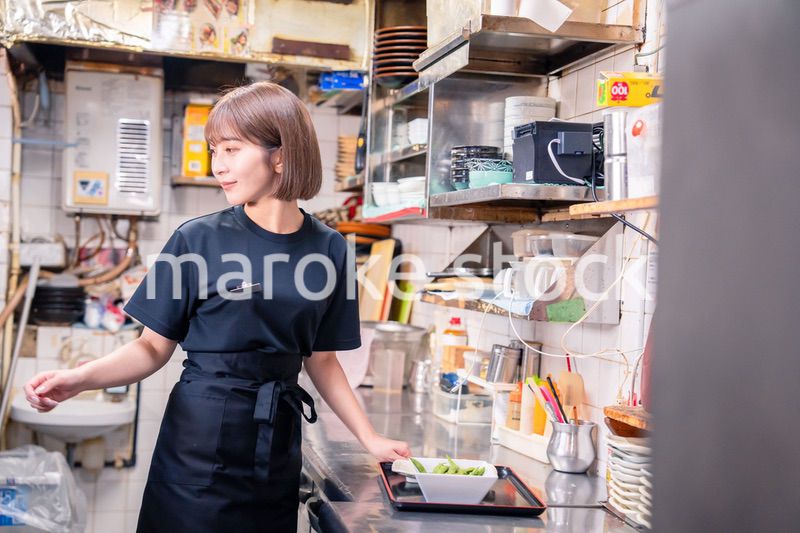 居酒屋の厨房で働くキッチンスタッフの女性