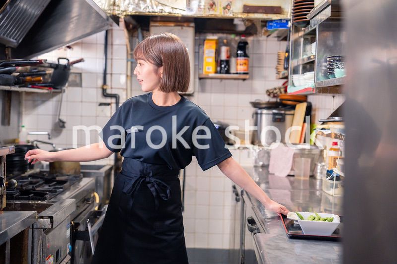 居酒屋の厨房で働くキッチンスタッフの女性