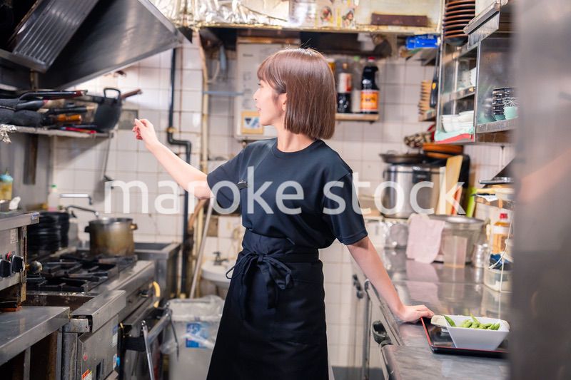 居酒屋の厨房で働くキッチンスタッフの女性