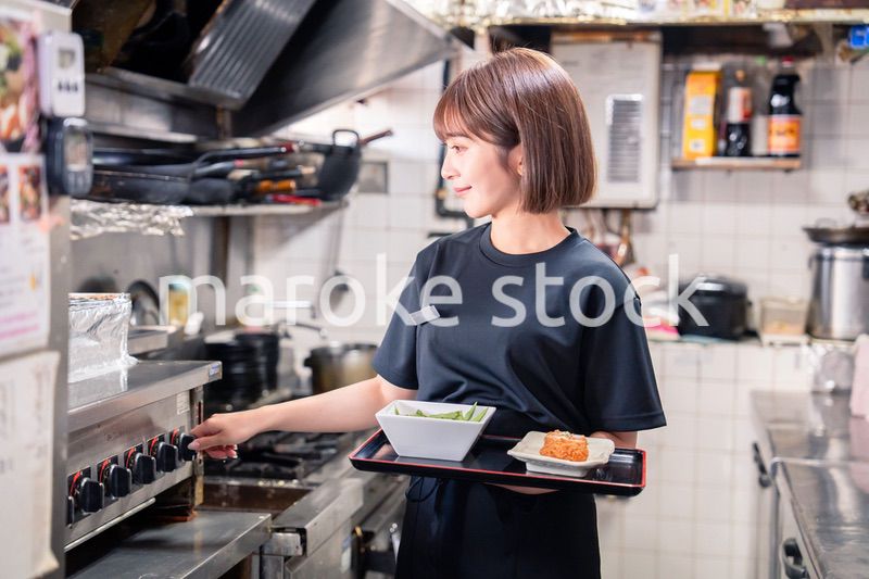 飲食店の厨房で働く若い女性のスタッフ