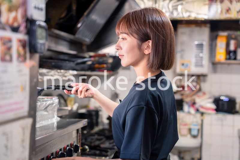 居酒屋の厨房で働くキッチンスタッフの女性