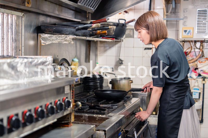 居酒屋の厨房で働くキッチンスタッフの女性
