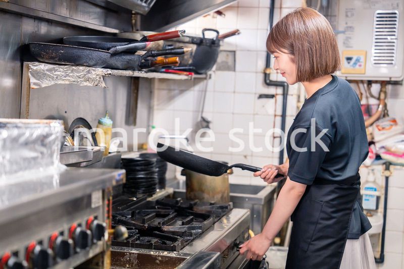 居酒屋の厨房で働くキッチンスタッフの女性