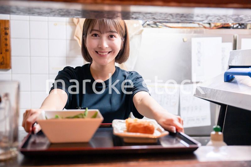 レストランでご飯を提供する若い女性のキッチンスタッフ