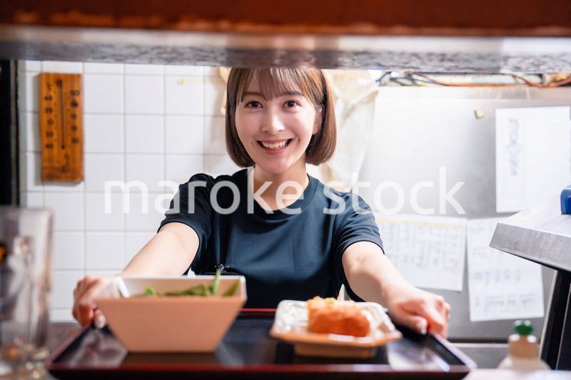 レストランでご飯を提供する若い女性のキッチンスタッフ