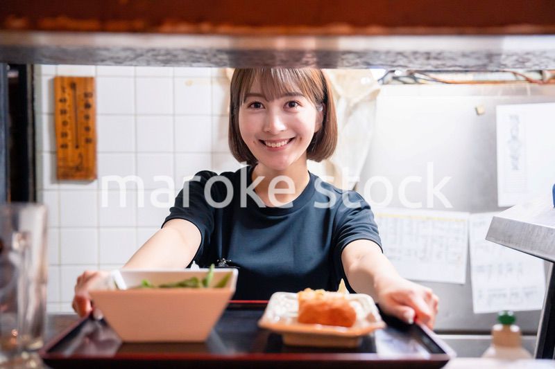 レストランでご飯を提供する若い女性のキッチンスタッフ