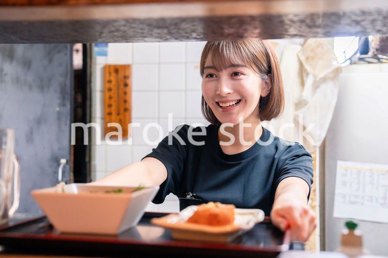 レストランでご飯を提供する若い女性のキッチンスタッフ