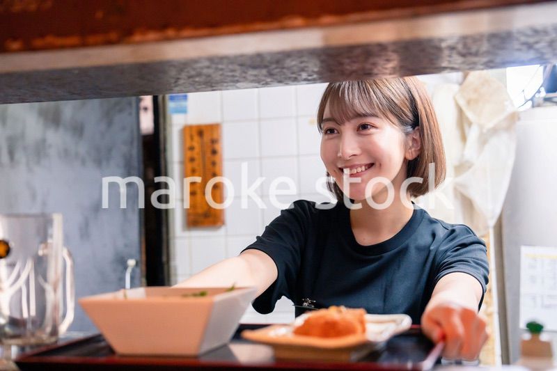 レストランでご飯を提供する若い女性のキッチンスタッフ