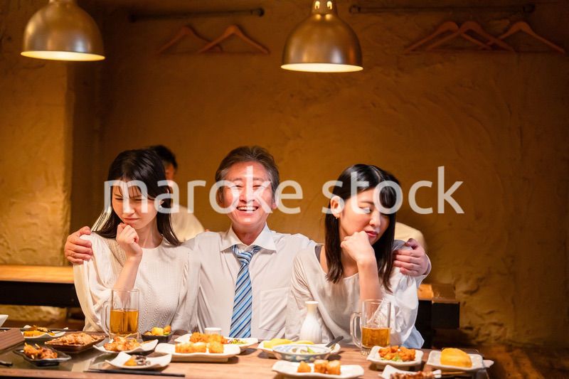 宴会の席で女性と肩を組むビジネスマン