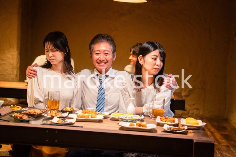 宴会の席で女性と肩を組むビジネスマン