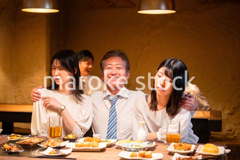 宴会の席で女性と肩を組むビジネスマン