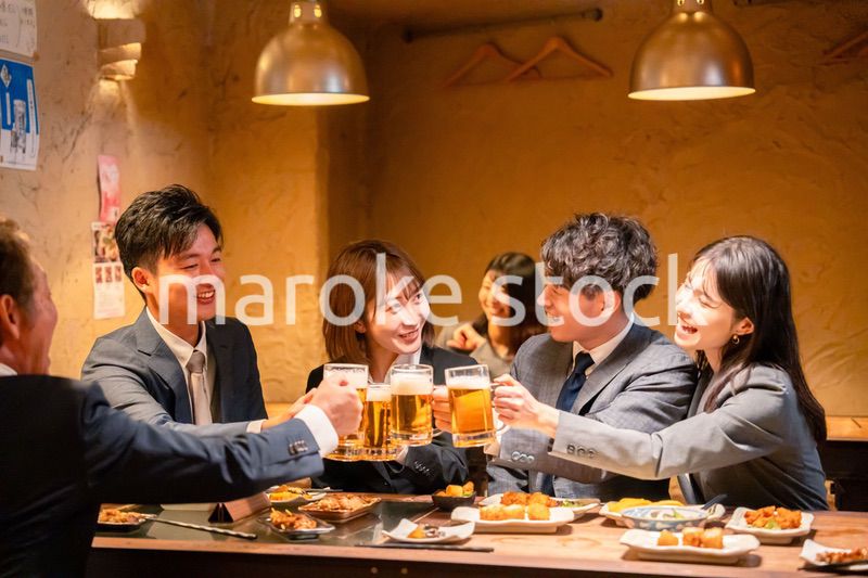 居酒屋で盛大に乾杯をするビジネスパーソン