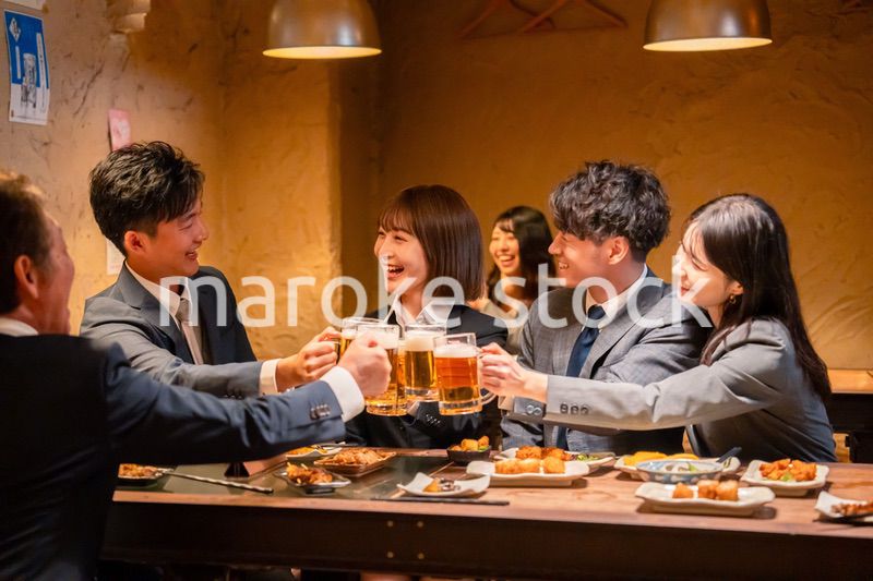 居酒屋で盛大に乾杯をするビジネスパーソン