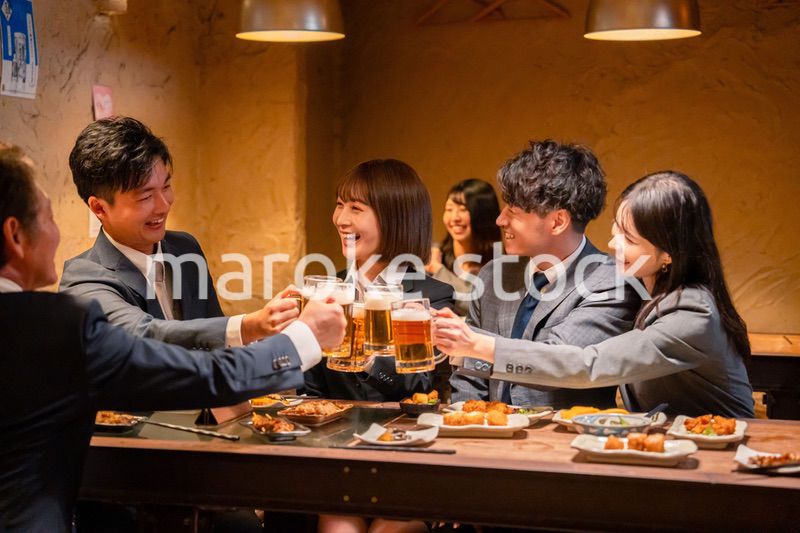 居酒屋で盛大に乾杯をするビジネスパーソン