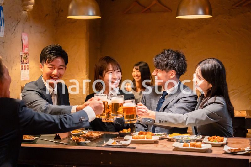 居酒屋で盛大に乾杯をするビジネスパーソン