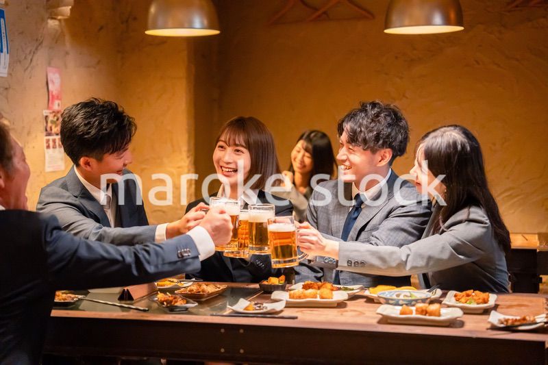 居酒屋で盛大に乾杯をするビジネスパーソン