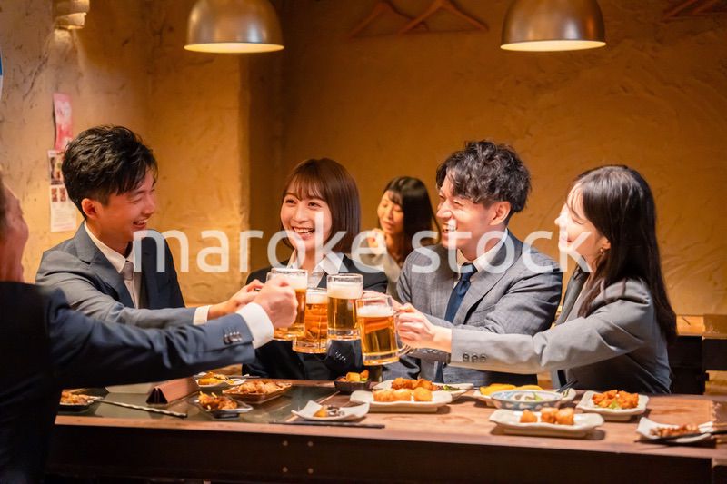 居酒屋で盛大に乾杯をするビジネスパーソン