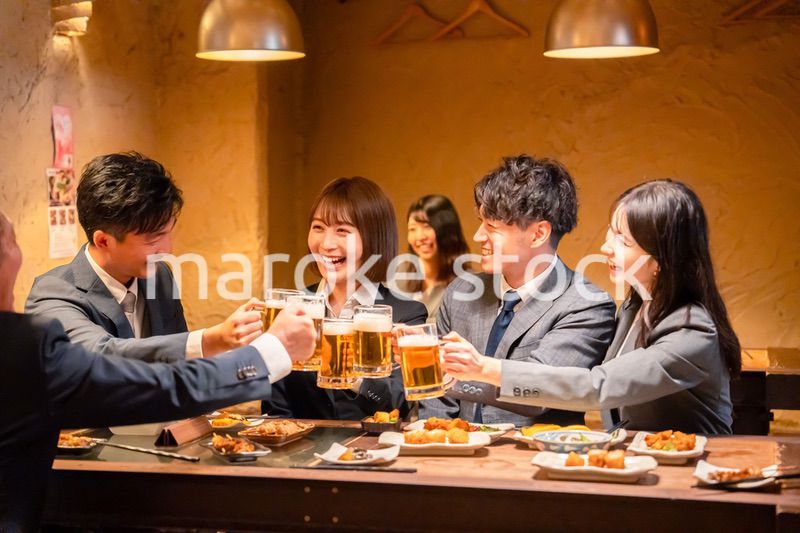 居酒屋で盛大に乾杯をするビジネスパーソン