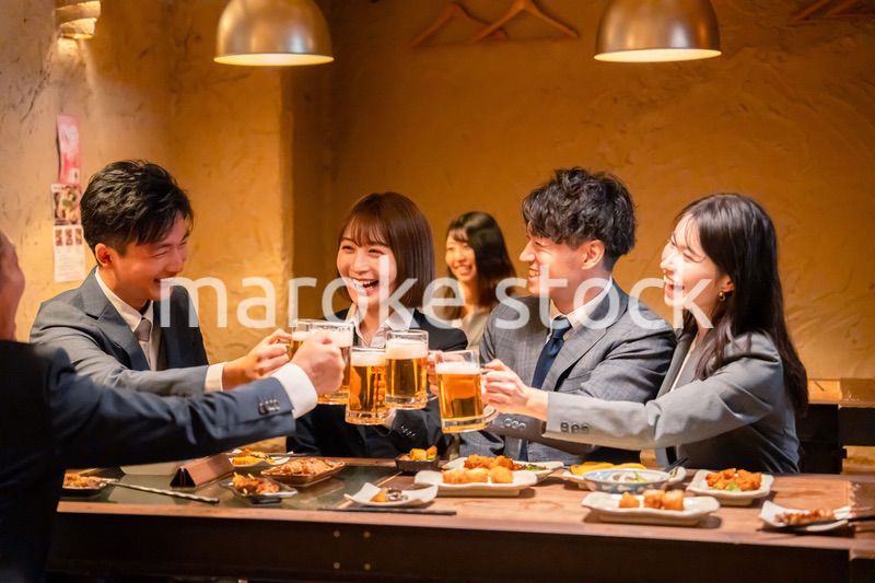 居酒屋で盛大に乾杯をするビジネスパーソン