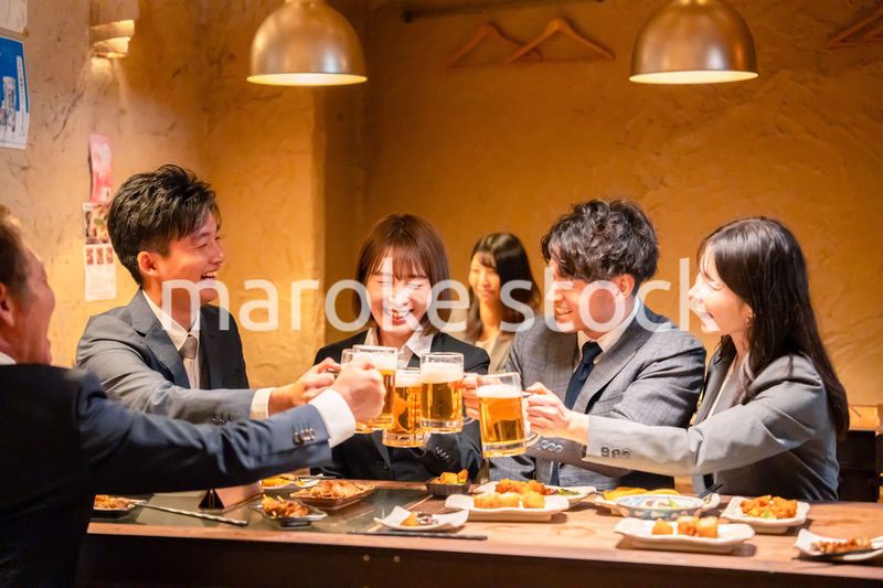 居酒屋で盛大に乾杯をするビジネスパーソン