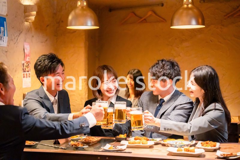 居酒屋で盛大に乾杯をするビジネスパーソン