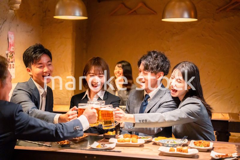 居酒屋で盛大に乾杯をするビジネスパーソン