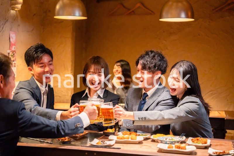 居酒屋で盛大に乾杯をするビジネスパーソン
