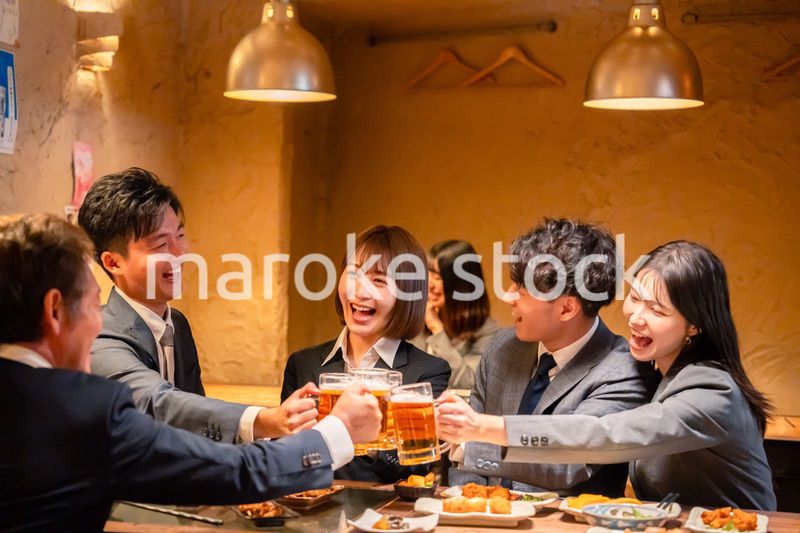 居酒屋で盛大に乾杯をするビジネスパーソン
