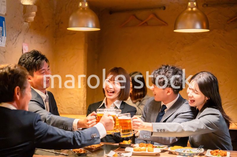 居酒屋で盛大に乾杯をするビジネスパーソン