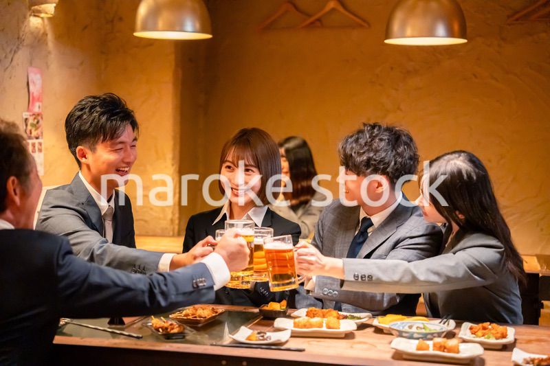 居酒屋で盛大に乾杯をするビジネスパーソン