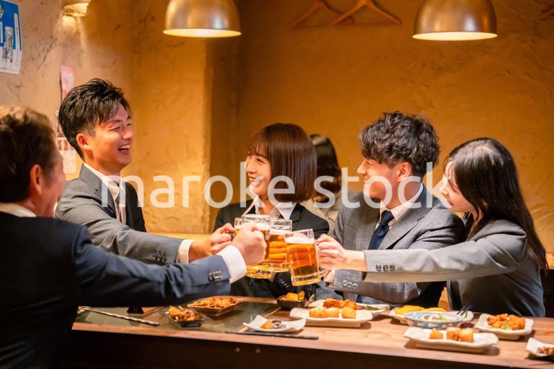 居酒屋で盛大に乾杯をするビジネスパーソン