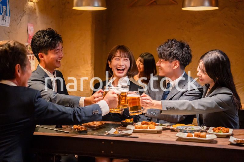 居酒屋で盛大に乾杯をするビジネスパーソン