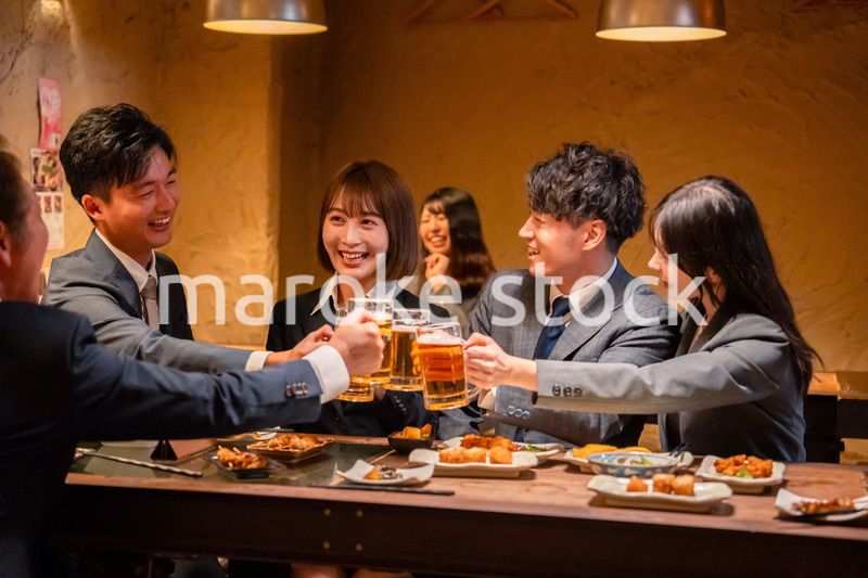 居酒屋で盛大に乾杯をするビジネスパーソン