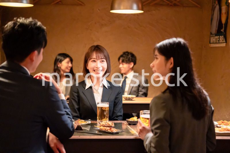 居酒屋で先輩社員とお酒を飲む新入社員