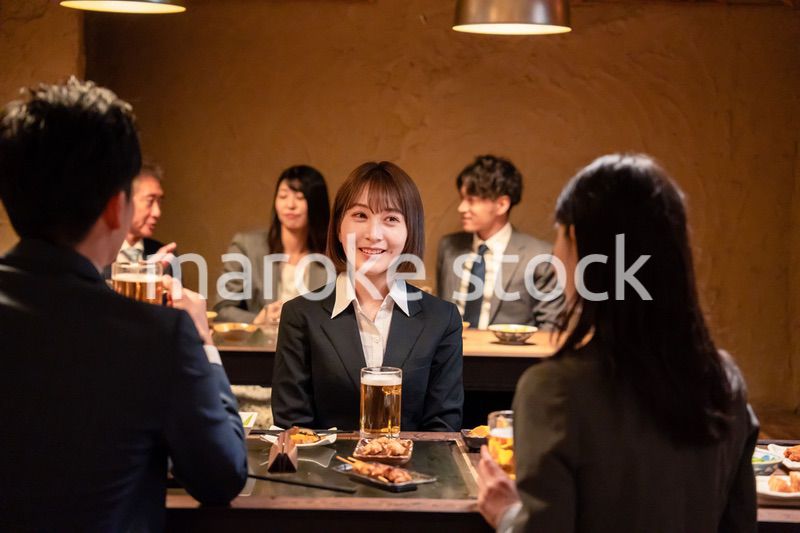 居酒屋で先輩社員とお酒を飲む新入社員