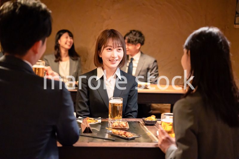 居酒屋で先輩社員とお酒を飲む新入社員