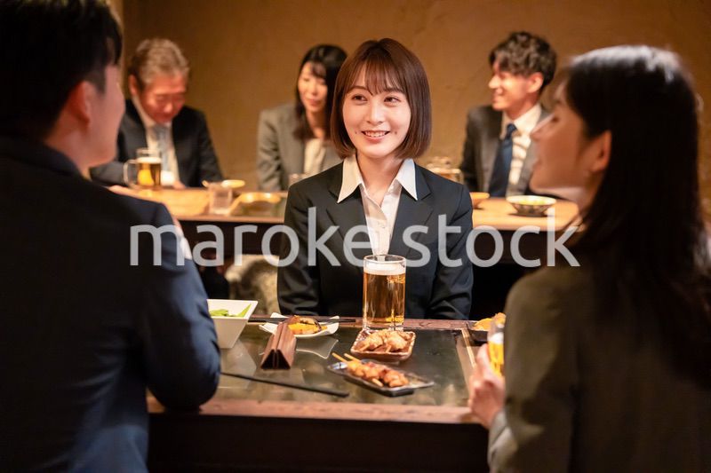 居酒屋で先輩社員とお酒を飲む新入社員