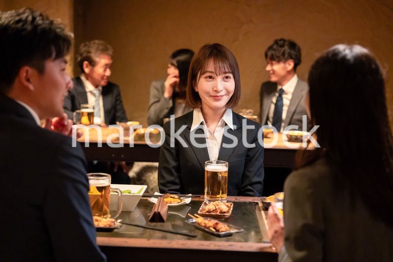 居酒屋で先輩社員とお酒を飲む新入社員