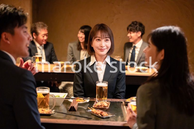 居酒屋で先輩社員とお酒を飲む新入社員