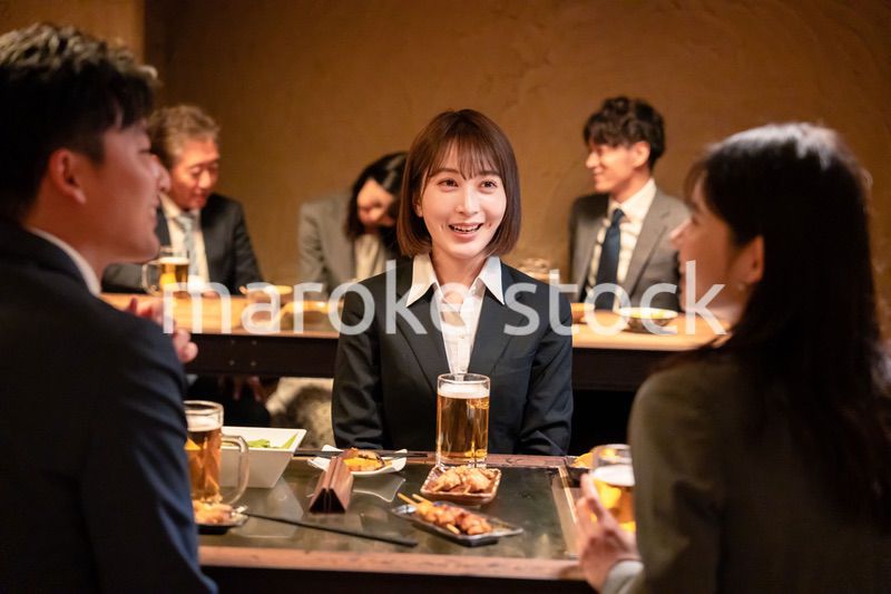 居酒屋で先輩社員とお酒を飲む新入社員