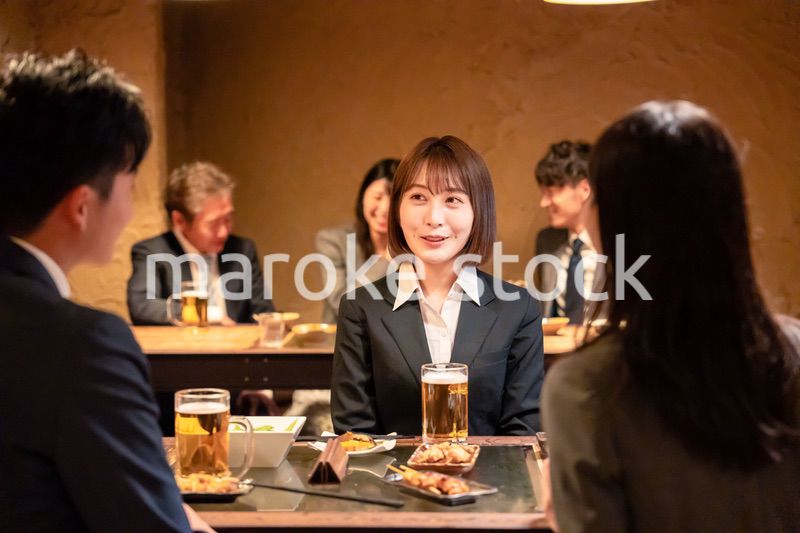 居酒屋で先輩社員とお酒を飲む新入社員