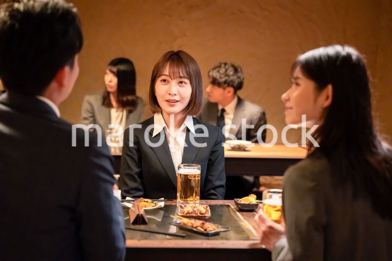居酒屋で先輩社員とお酒を飲む新入社員