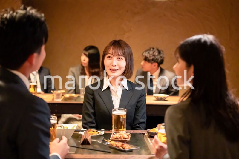 居酒屋で先輩社員とお酒を飲む新入社員