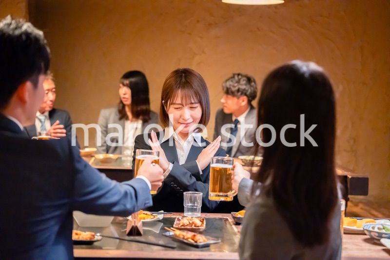 居酒屋で先輩社員にアルコールを勧められて断る女性社員