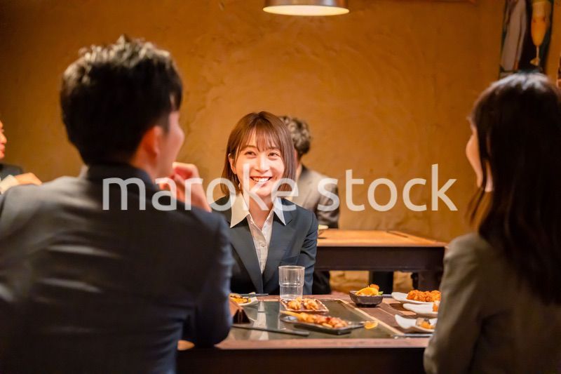 先輩社員と居酒屋で話をするフレッシュな女性