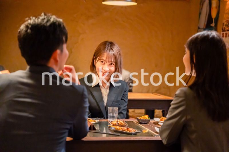 先輩社員と居酒屋で話をするフレッシュな女性