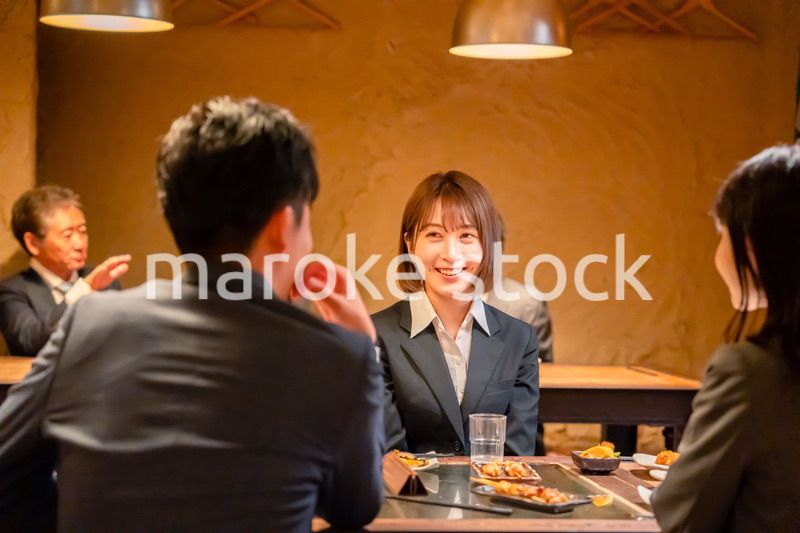 先輩社員と居酒屋で話をするフレッシュな女性