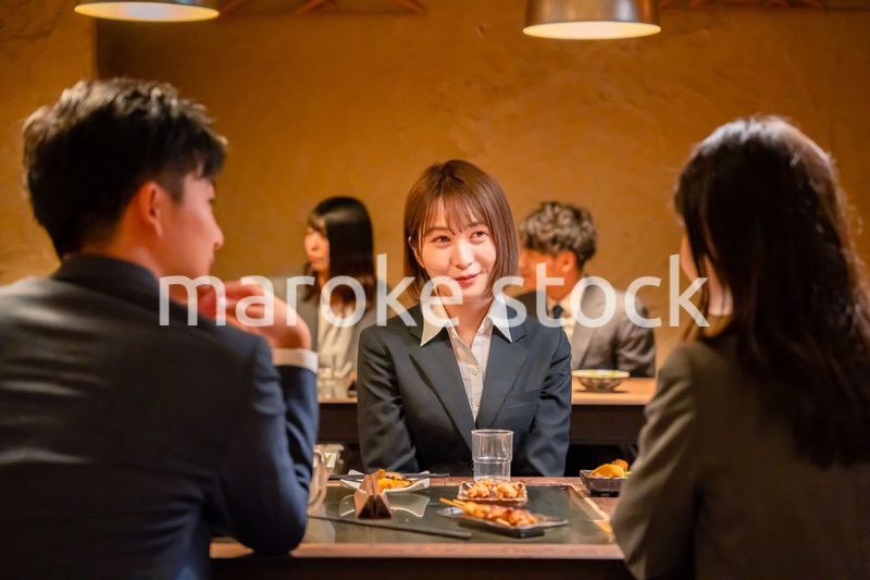 先輩社員と居酒屋で話をするフレッシュな女性